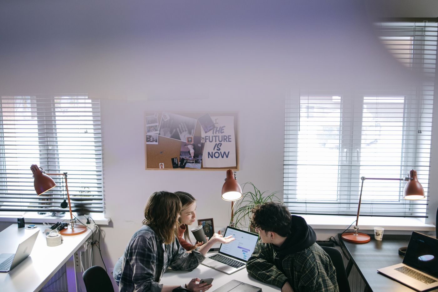 Colleagues discussing work around a laptop in an office